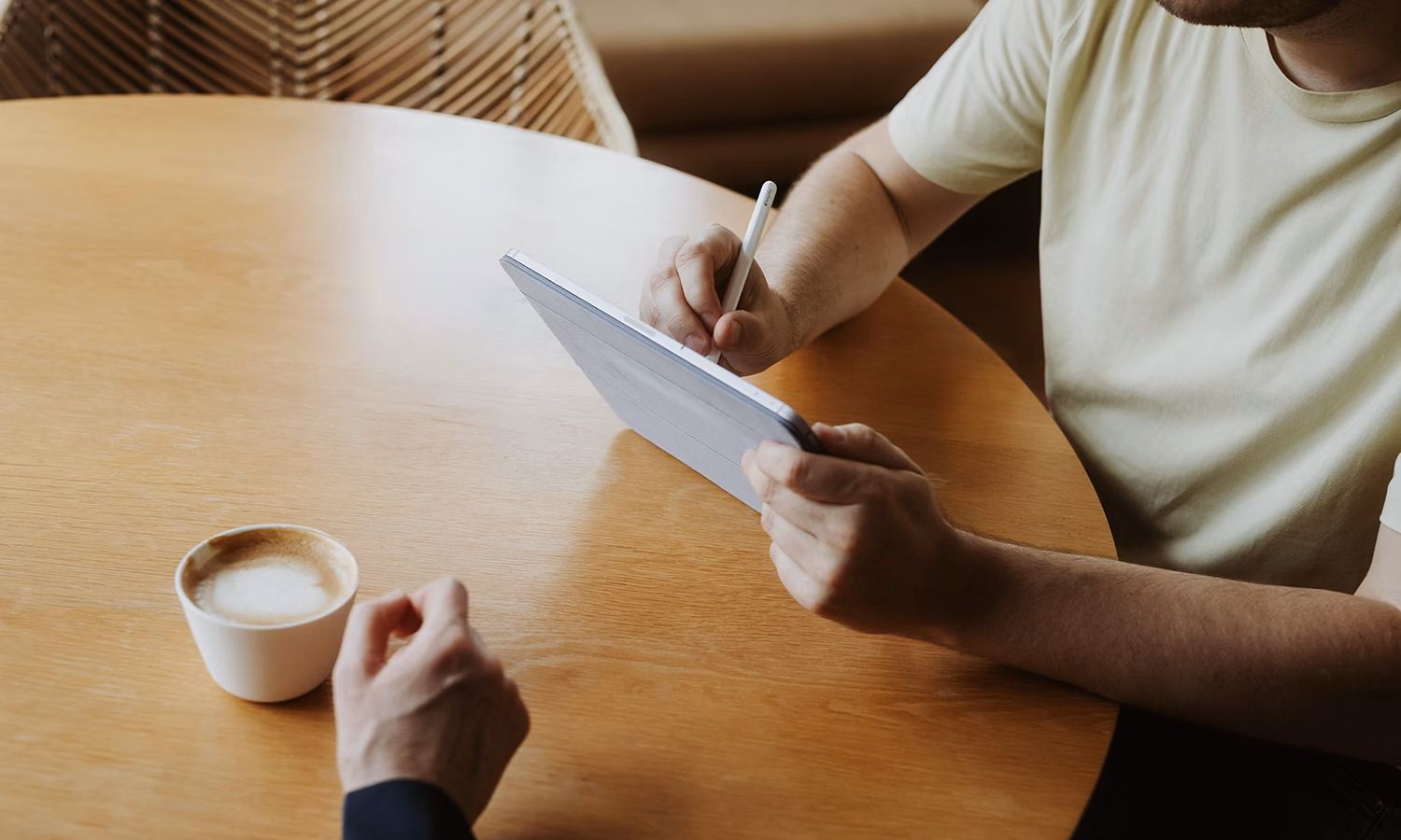 Diskussion am Tisch, die Hände zeigen auf ein Tablet